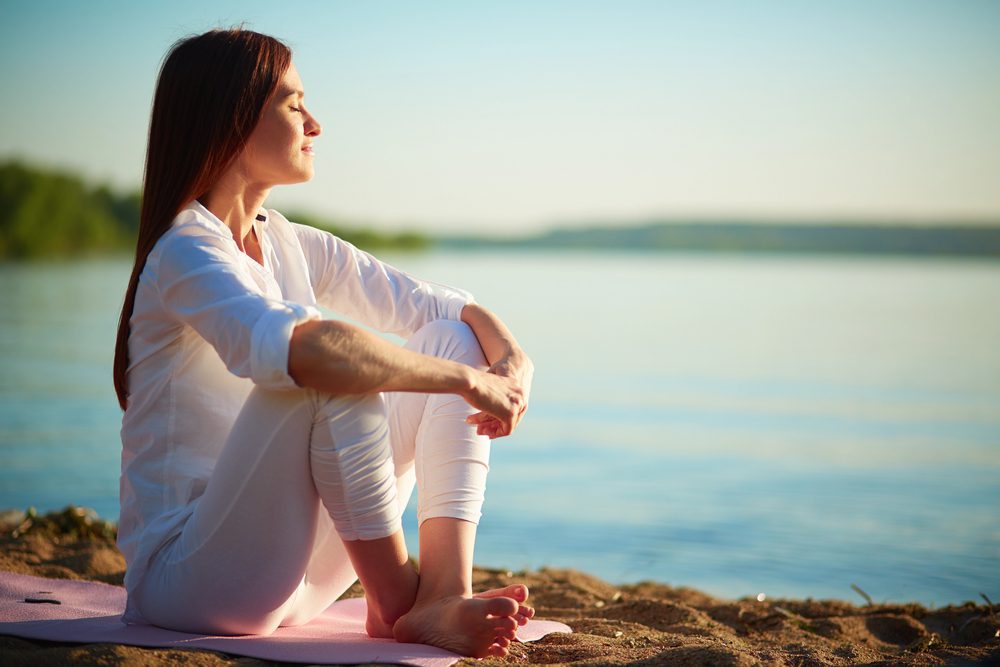 woman meditating on a sandy beach